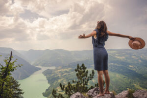 Image of a woman on a cliff holding a hat. We have an anxiety therapist in Columbia, MD. We can help you get started in anxiety treatment in Baltimore, MD. Call today to start reducing your anxiety symptoms with anxiety therapy in the Washington D.C. area.