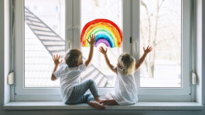 Image of kid touching a rainbow painted on a window. Showing how through child therapy in the Washington DC area your child can start to shine. Painting and play therapy can help foster communication in children's therapy in Maryland.
